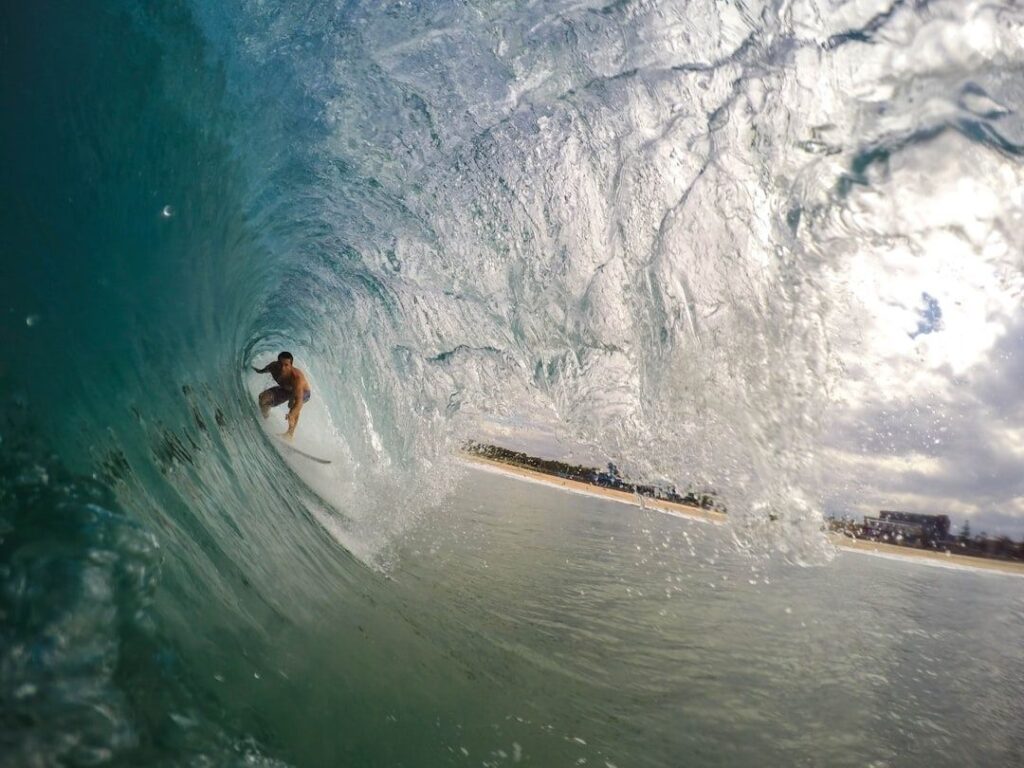 Surfer crouches deep on a surfboard inside a breaking wave