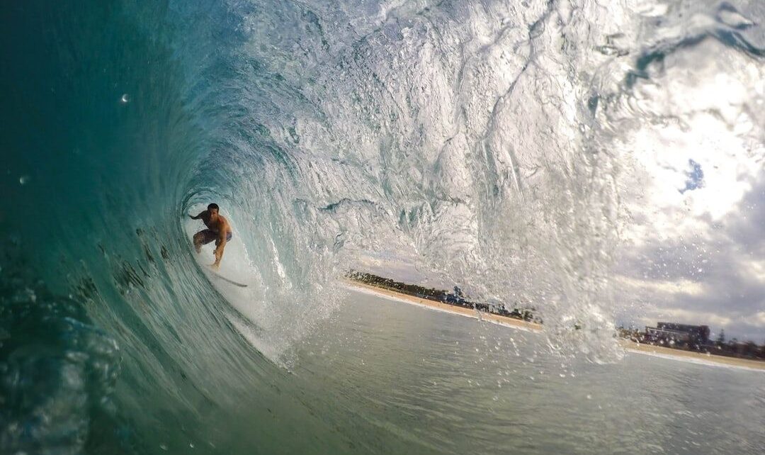 Surfer crouches deep on a surfboard inside a breaking wave