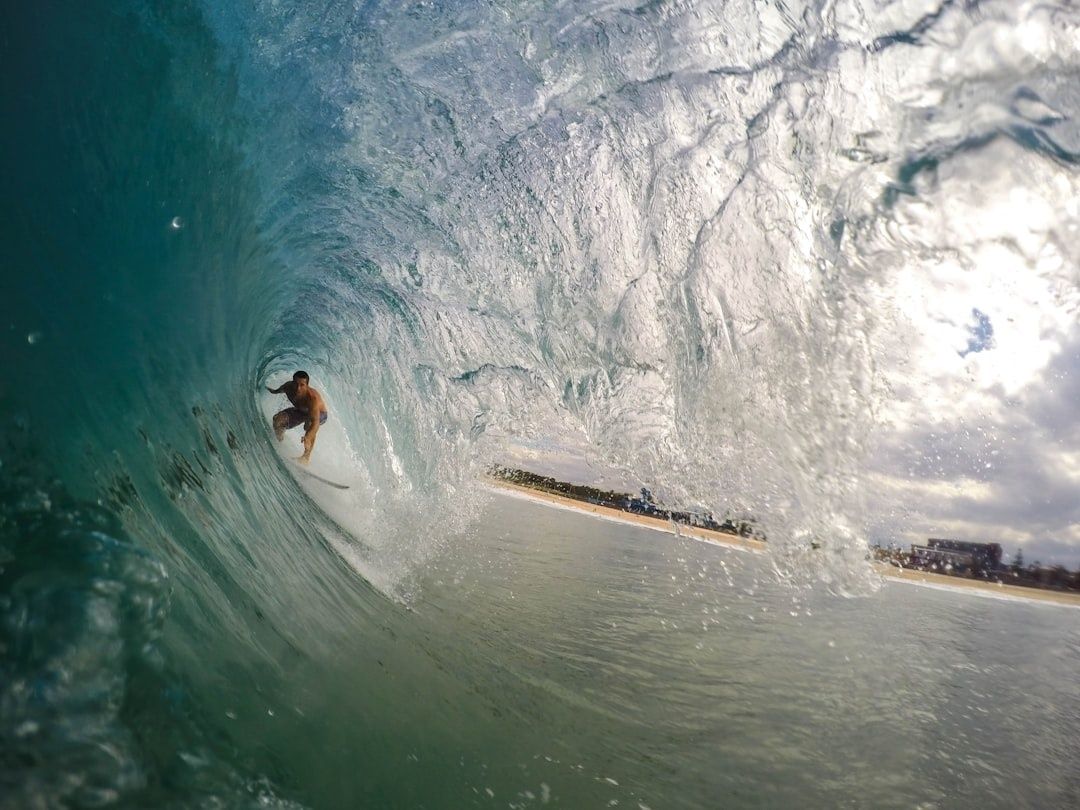 Surfer crouches deep on a surfboard inside a breaking wave