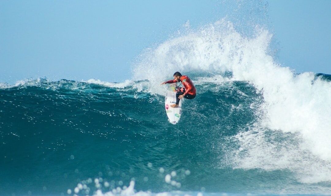 Surfer launches off a powerful breaking wave amid heavy spray